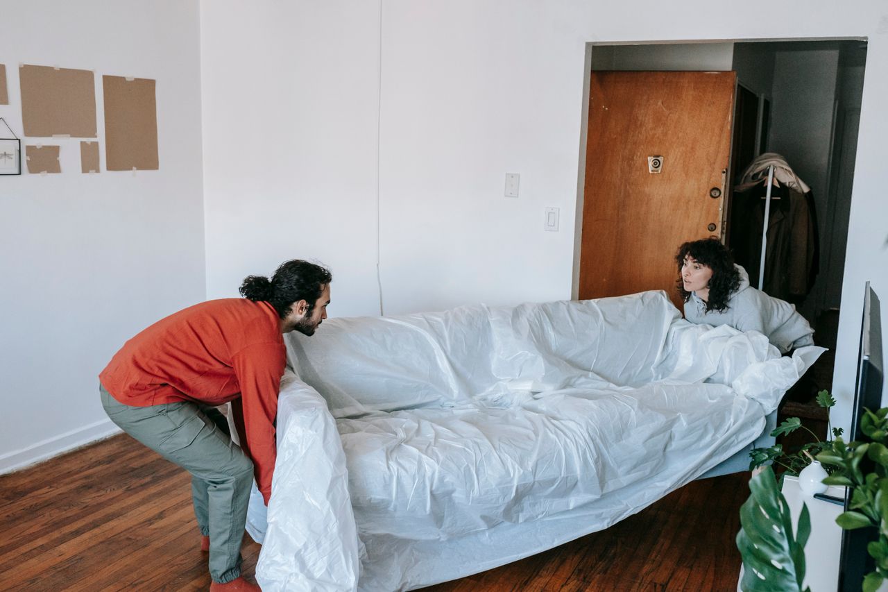 home-img A couple collaboratively lifting a couch while moving into a new apartment.